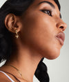Gift With Purchase Heart Hoop Charms: Close-up of gold hoop earrings with heart charms, worn by a woman with long black hair.