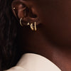 Close-up of a woman's ear wearing a handcrafted 14k solid gold Letter Stud earring, showcasing its elegant initial design.