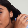 Close-up of a woman's face showcasing Patra Huggie Hoops, handcrafted 14k gold earrings, highlighting their elegant design.