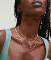 Close-up of a woman wearing a Diamond Letter Charm on a necklace, paired with matching earrings, showcasing elegant body jewelry.