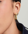 Close-up of a woman's ear wearing Block Large Hoops, inspired by angular, modernist architecture, highlighting the earrings' bold and geometric design suitable for everyday wear.