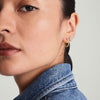 Close-up of a woman's face showcasing Pavé Diamond Small Hoops, handcrafted in recycled 14k gold, worn on her ear.