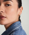 Close-up of a woman's face showcasing Pavé Diamond Small Hoops, handcrafted in recycled 14k gold, worn on her ear.
