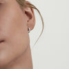 Close-up of a woman's ear wearing Bold Huggie Hoops, showcasing the earrings' sleek, elegant design.