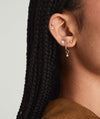 Close-up of a woman's ear displaying a Single Tiny Pear Diamond Flat Back Stud, a delicate 14k gold earring with a responsibly sourced diamond.
