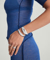Silver 13mm Dome Cuff Bracelet elegantly adorns a woman's wrist, paired with another bracelet, enhancing the sophisticated look of her blue dress.