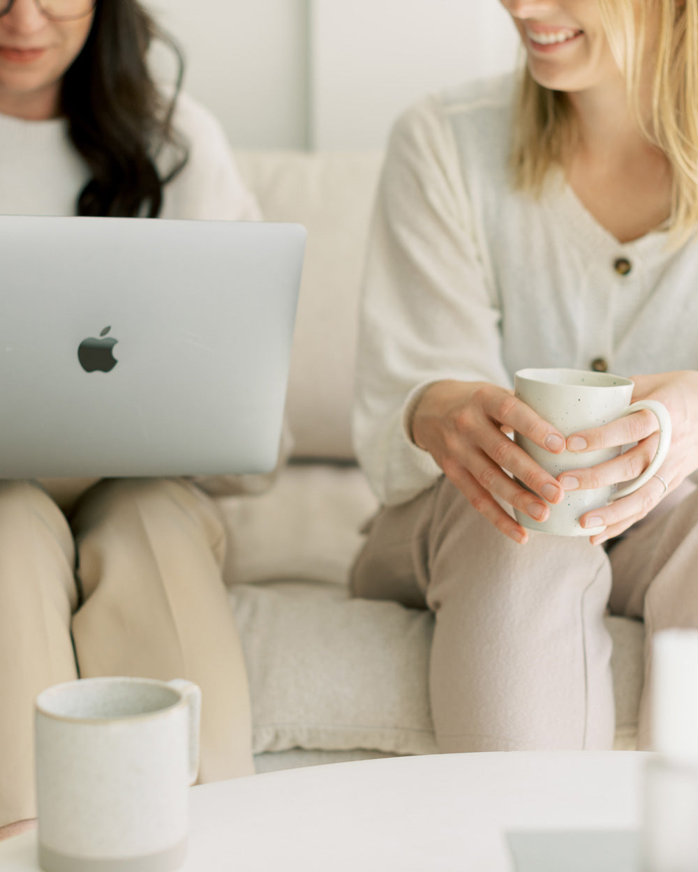 Entrepreneurs sitting on a coach drinking coffee and working on a computer