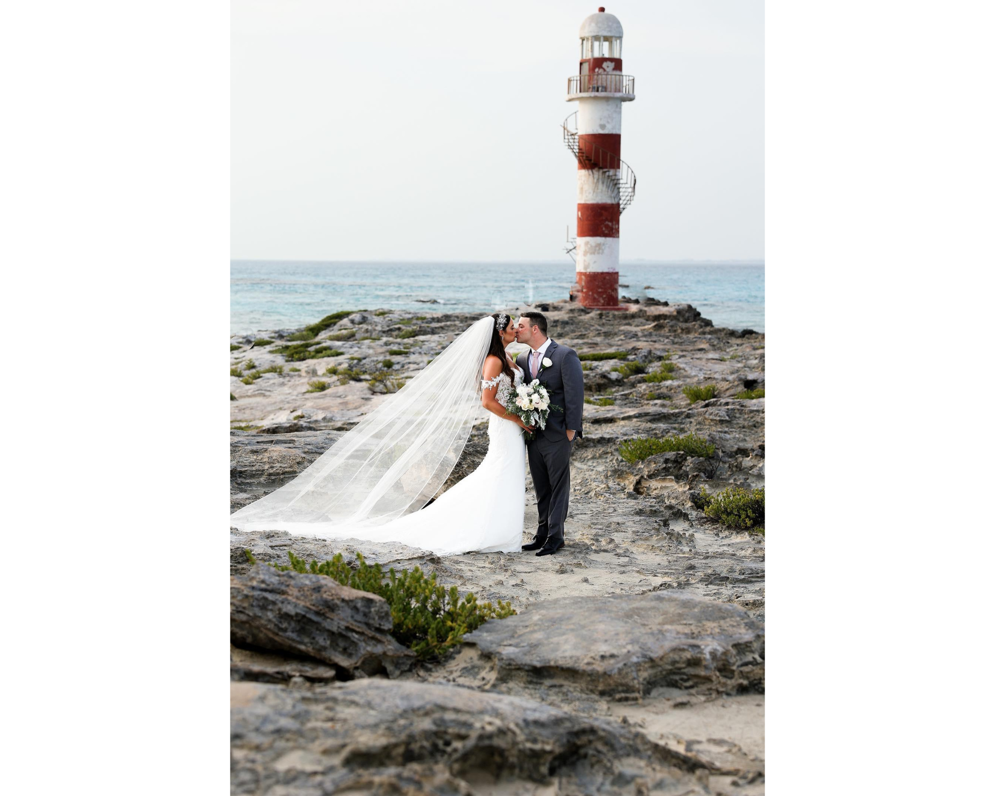 A beautiful bride and her new husband by a lighthouse. She's wearing her hair down with a custom Swarovski crystal hair vine.