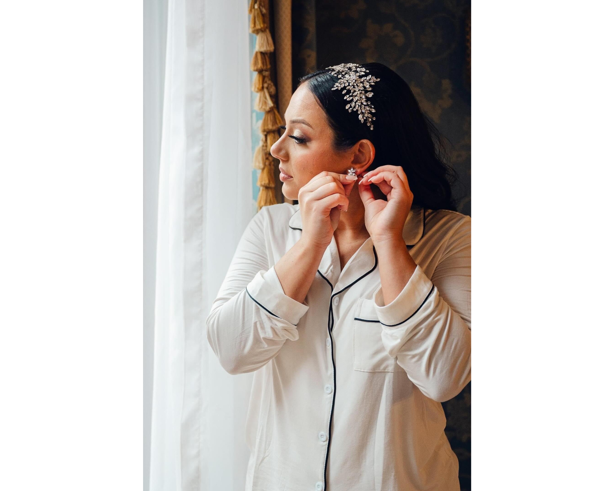 A brunette bride getting ready for her wedding. She is wearing white silk PJs and a Swarovski crystal bridal comb.