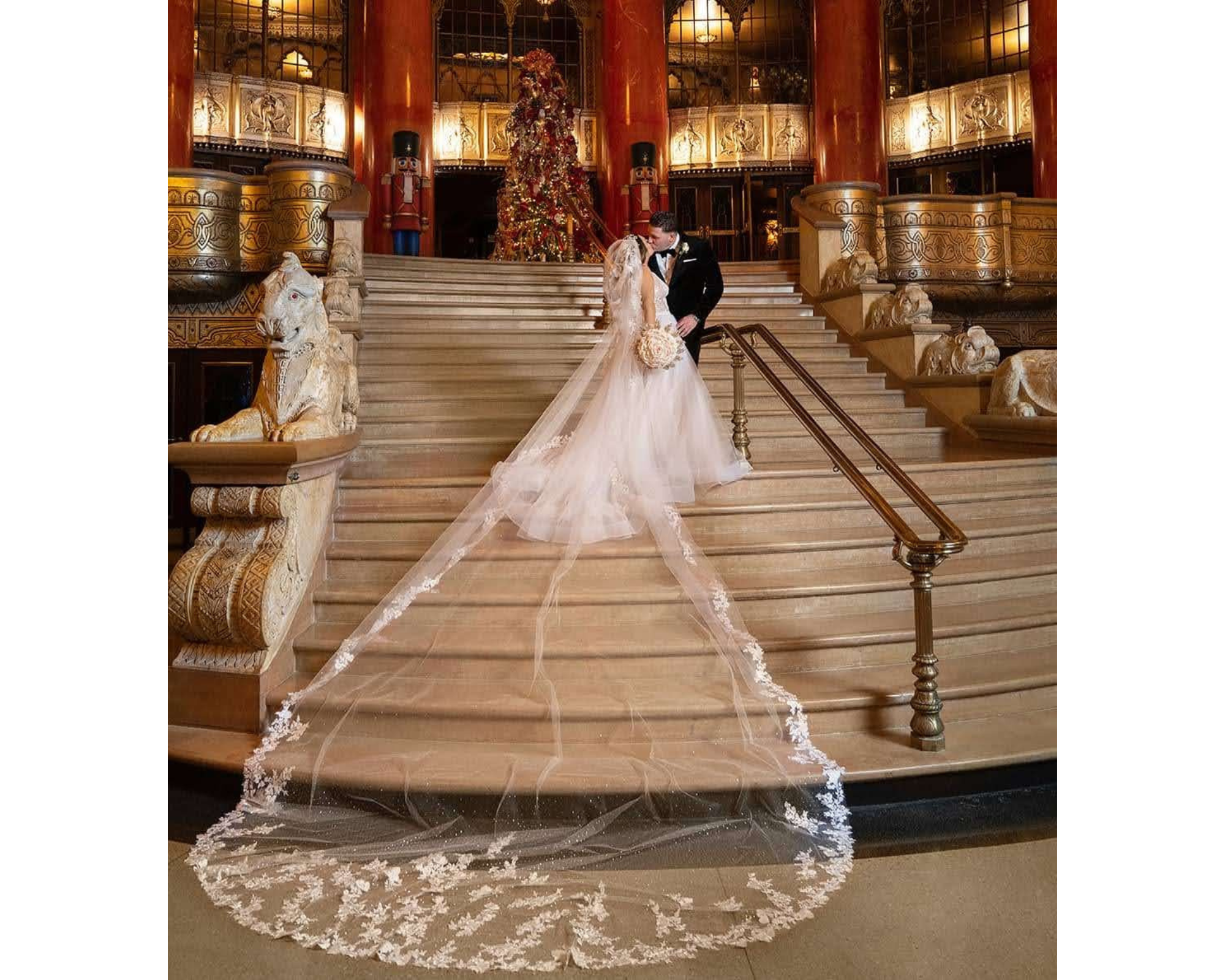 A gorgeous bride kissing her groom while her lace edged cathedral veil trails down steps.