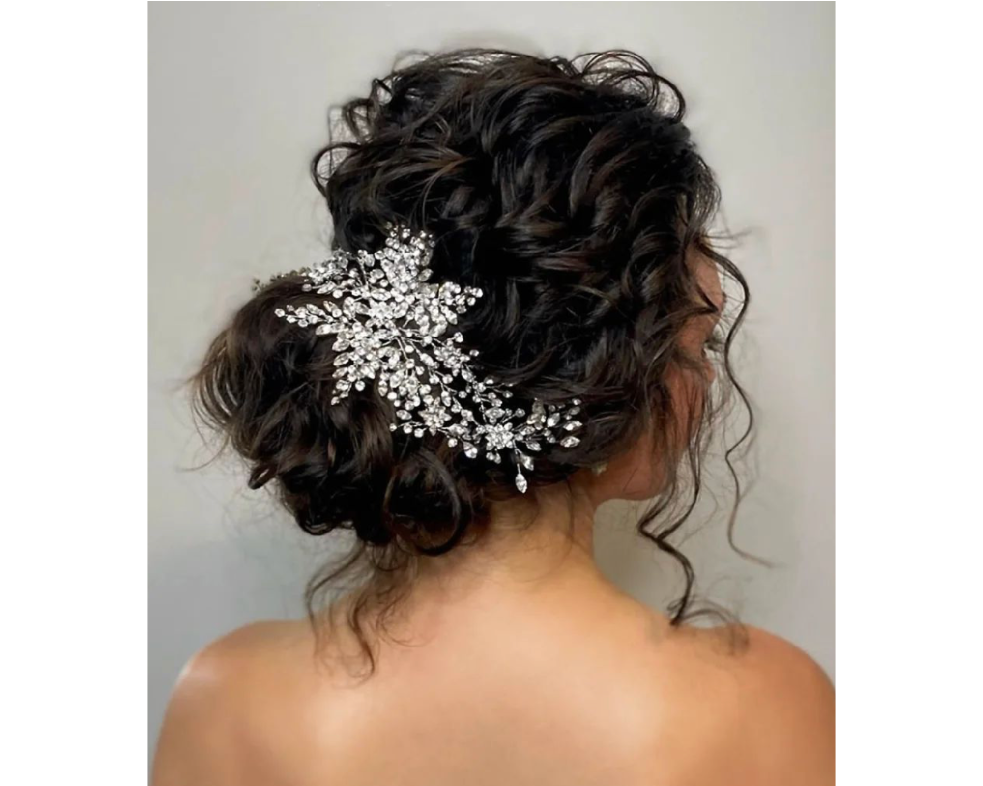 A bride wearing her curly hair in a romantic updo with a Swarovski crystal wedding tiara.