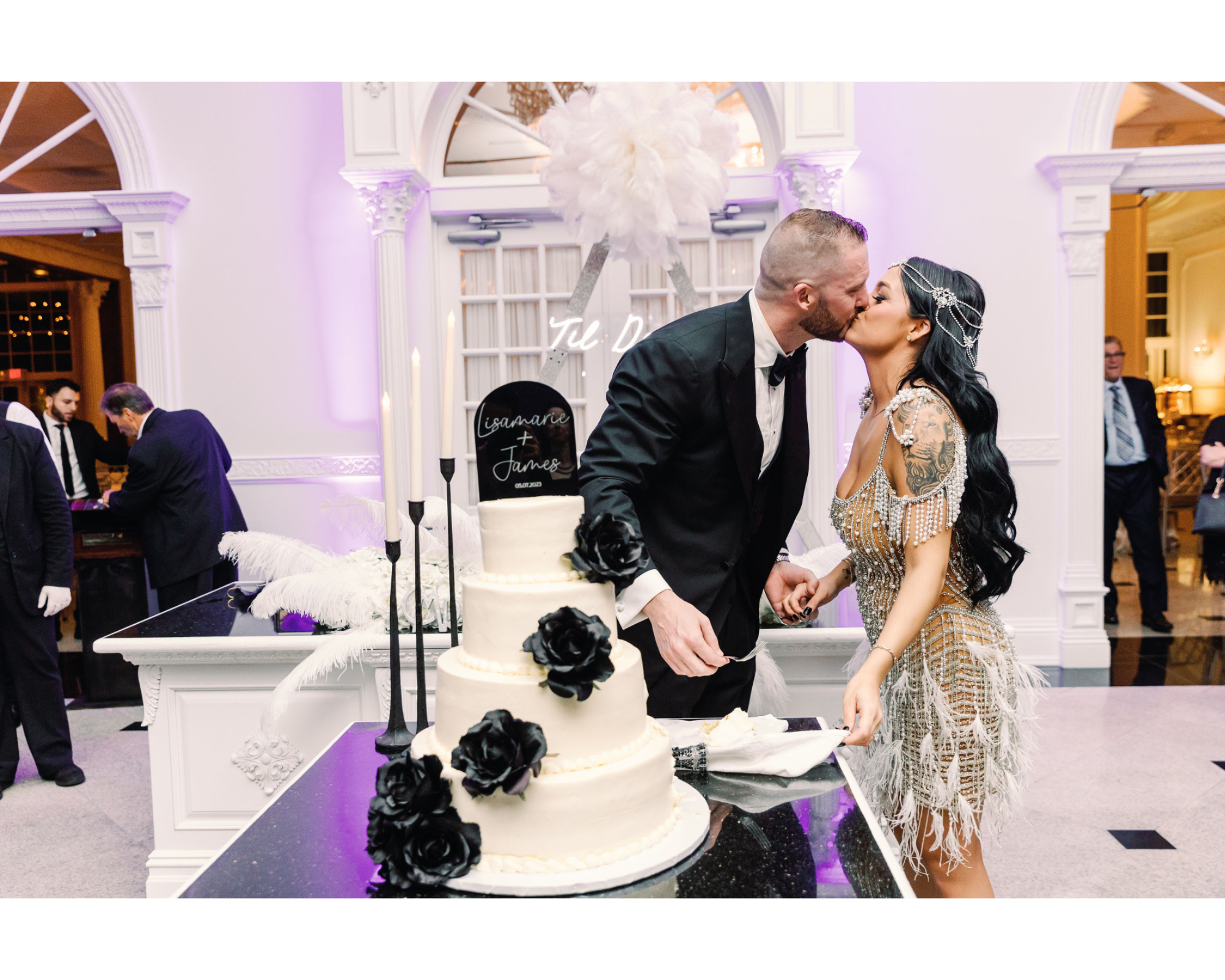 Great Gatsby-inspired bride cutting her black and white cake with her handsome groom. She's wearing a Swarovski-crystal bridal halo headpiece and beaded gown.