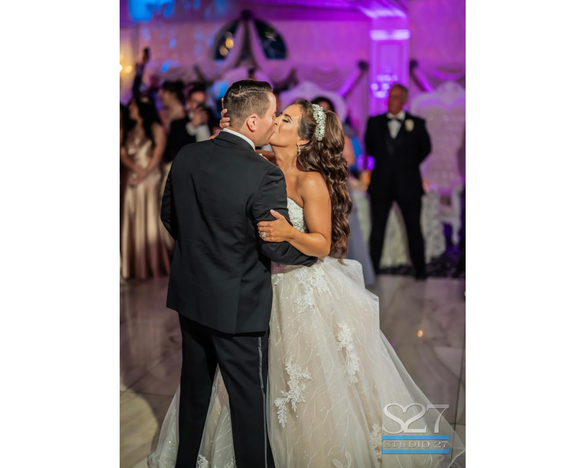 A beautiful bride with her groom on a lit-up dance floor. She is wearing a lace wedding dress and sparkling bridal headband.