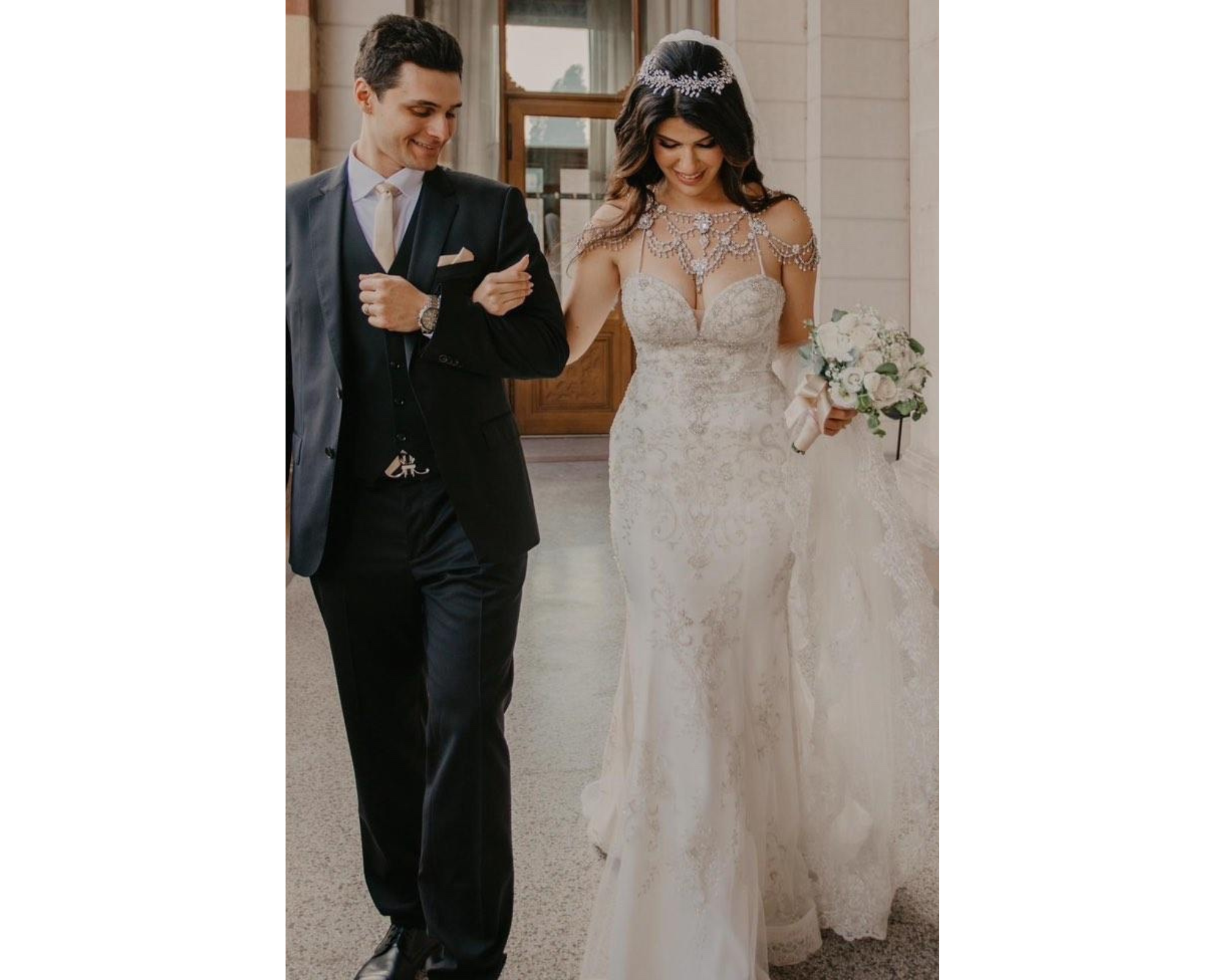 Our bride walking with her groom. She’s wearing her lace dress, Swarovski crystal wedding dress jewelry, and a wedding headpiece.