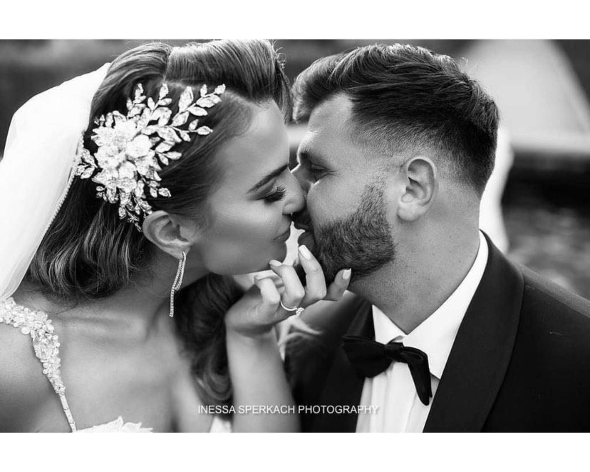 A beautiful bride kisses her groom. She wears a custom crystal rose comb created by Bridal Styles Boutique.