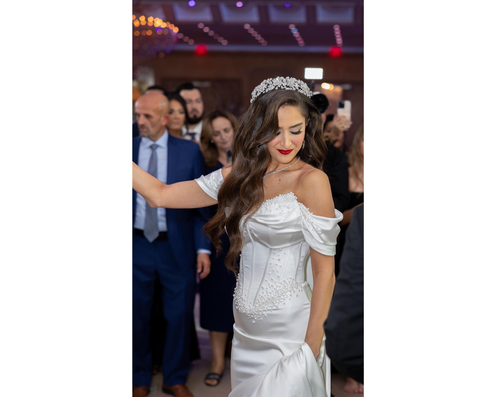 A bride at her reception. and she is wearing  her second dress,  Swarovski crystal headpiece, earrings, and necklace.