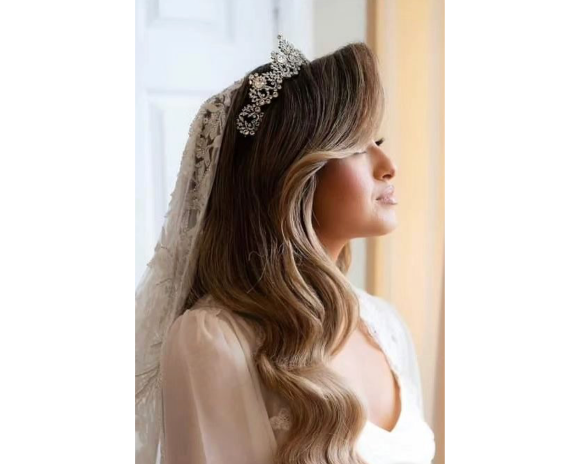 A lovely bride with her blond hair in soft waves wearing a veil and glittering Swarovski crystal bridal tiara.