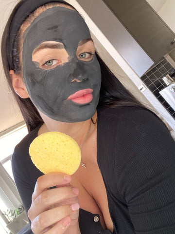 A woman adding charcoal clay masks to her regular skincare routine.