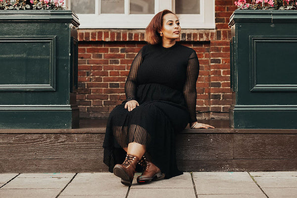 beautiful plus size woman wearing a black dress sitting on pavement
