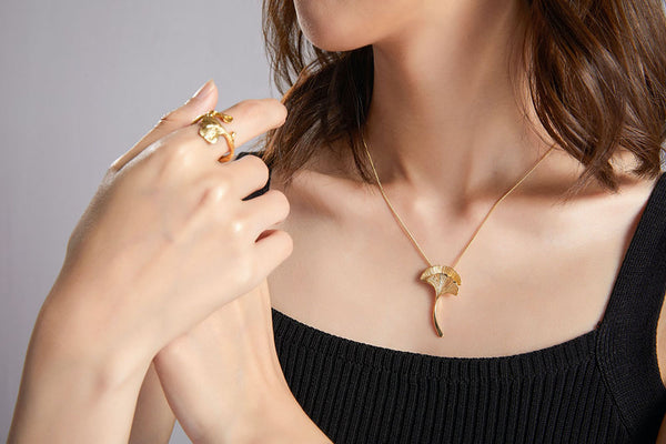 close up shot of a woman in a little black dress wearing matching gold fashion ring and necklace