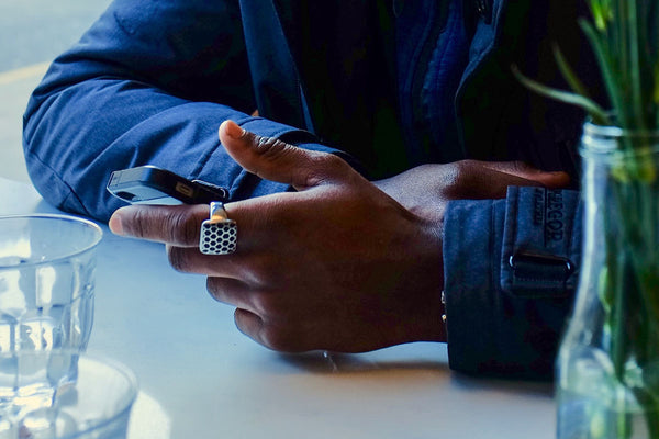 close up shot of man's hand wearing a fashion ring holding a black smartphone
