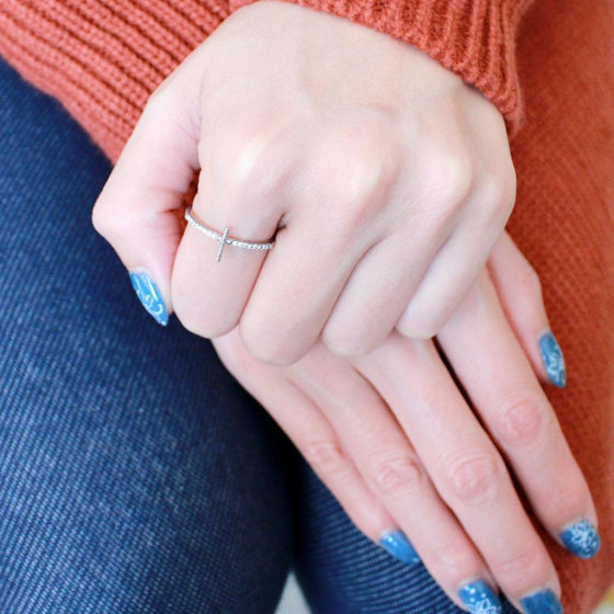 woman with blue nails wearing the Stainless Steel Minimal Cross Ring and an orange sweater