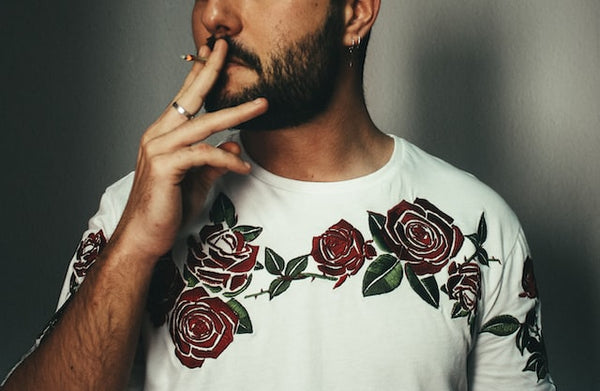 man wearing a ring and a white shirt with red roses design