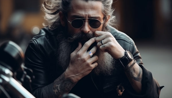 man with sunglasses wearing a biker ring and sitting on his motorcycle
