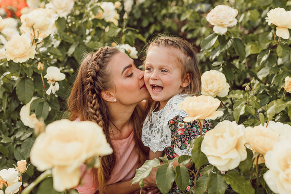mother kissing daughter surrounded by flowers