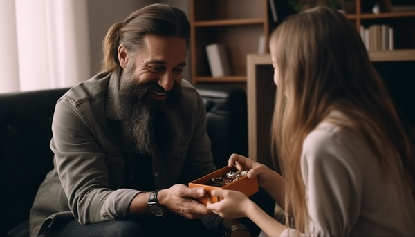 smiling bearded dad receiving a small ring box from smiling preteen daughter in the living room