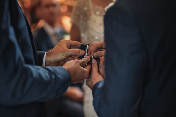 two gay men holding a ring box with men's engagement ring