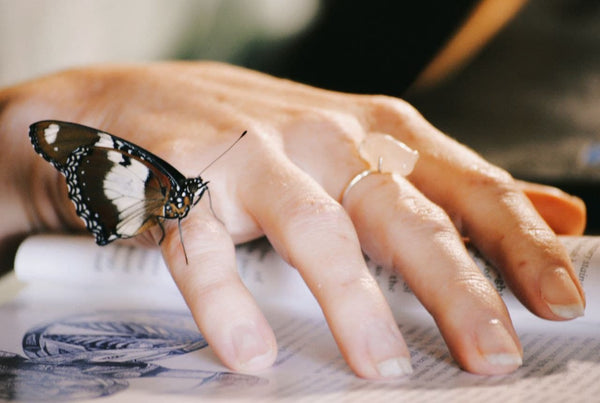 woman's hand wearing crystal fashion ring with a butterfly on her pinkie finger