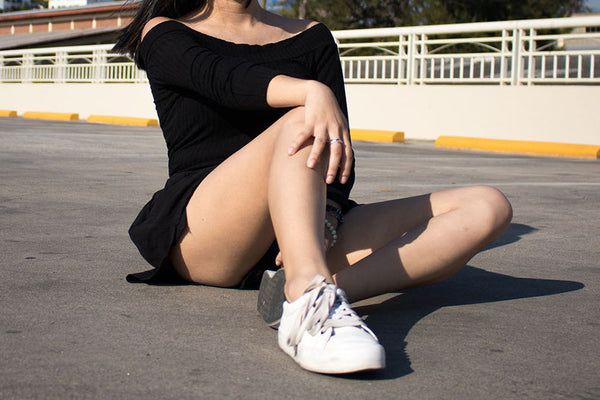 woman wearing a little black dress and white sneakers