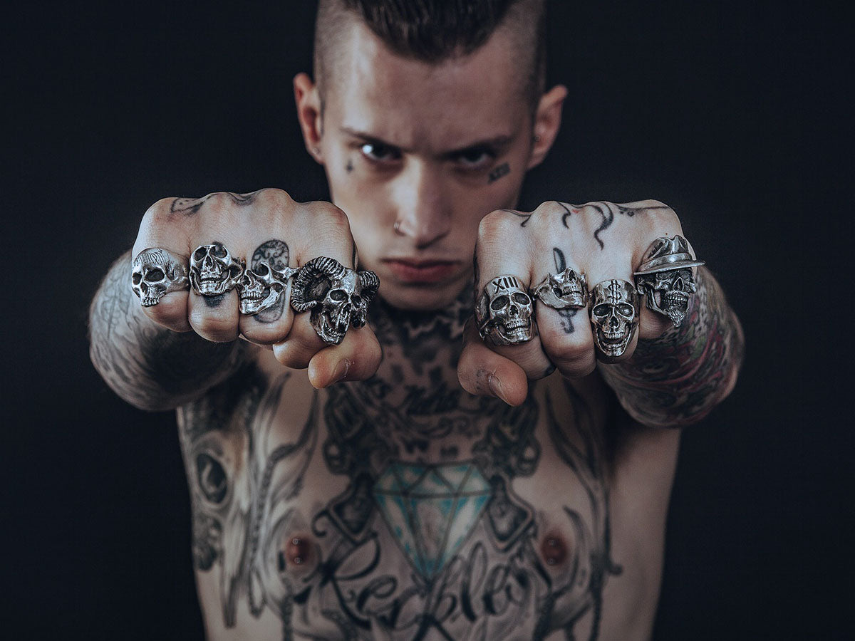 Tattooed man showing off his fingers with skull rings