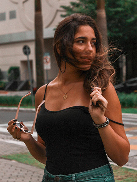 Woman wearing a black tank top and a minimalist necklace in summer