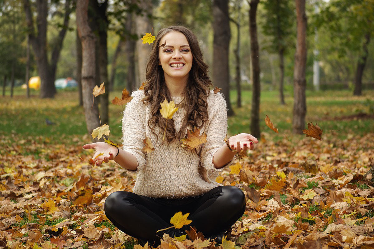 Woman sitting on leaves in Fall