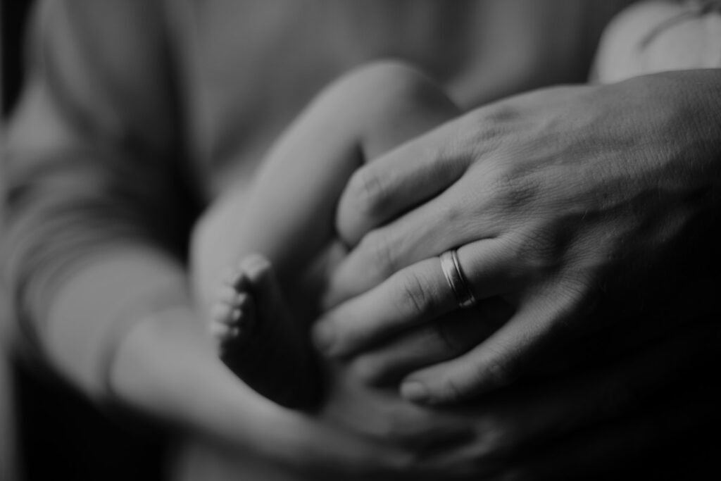 black and white photo of daddy wearing a ring holding his new baby