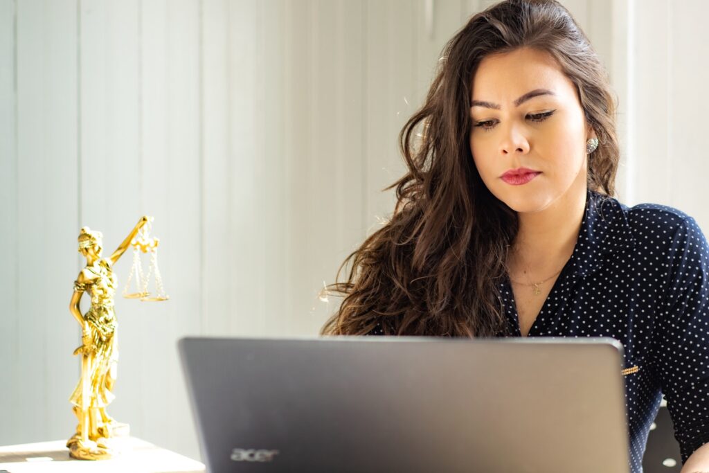 brunette woman wearing earrings working on her laptop