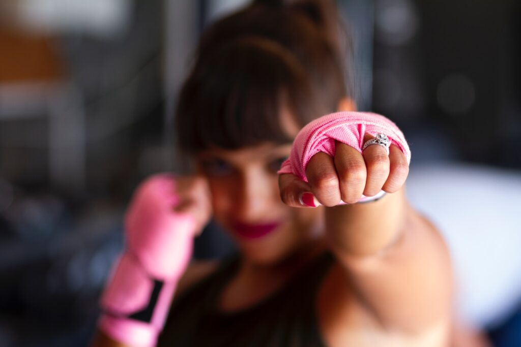 empowered woman in a boxing pose wearing a fashion ring and pink bandages on hands