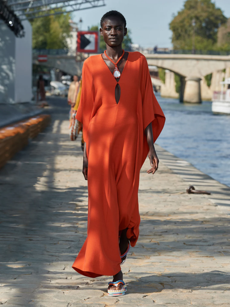 model in long orange dress wearing a statement pearl necklace at Chloé’s Spring/Summer 2022 Runway