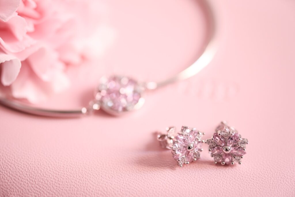 cz crystal flower earrings and cz pendant necklace in the background on top of a pink surface