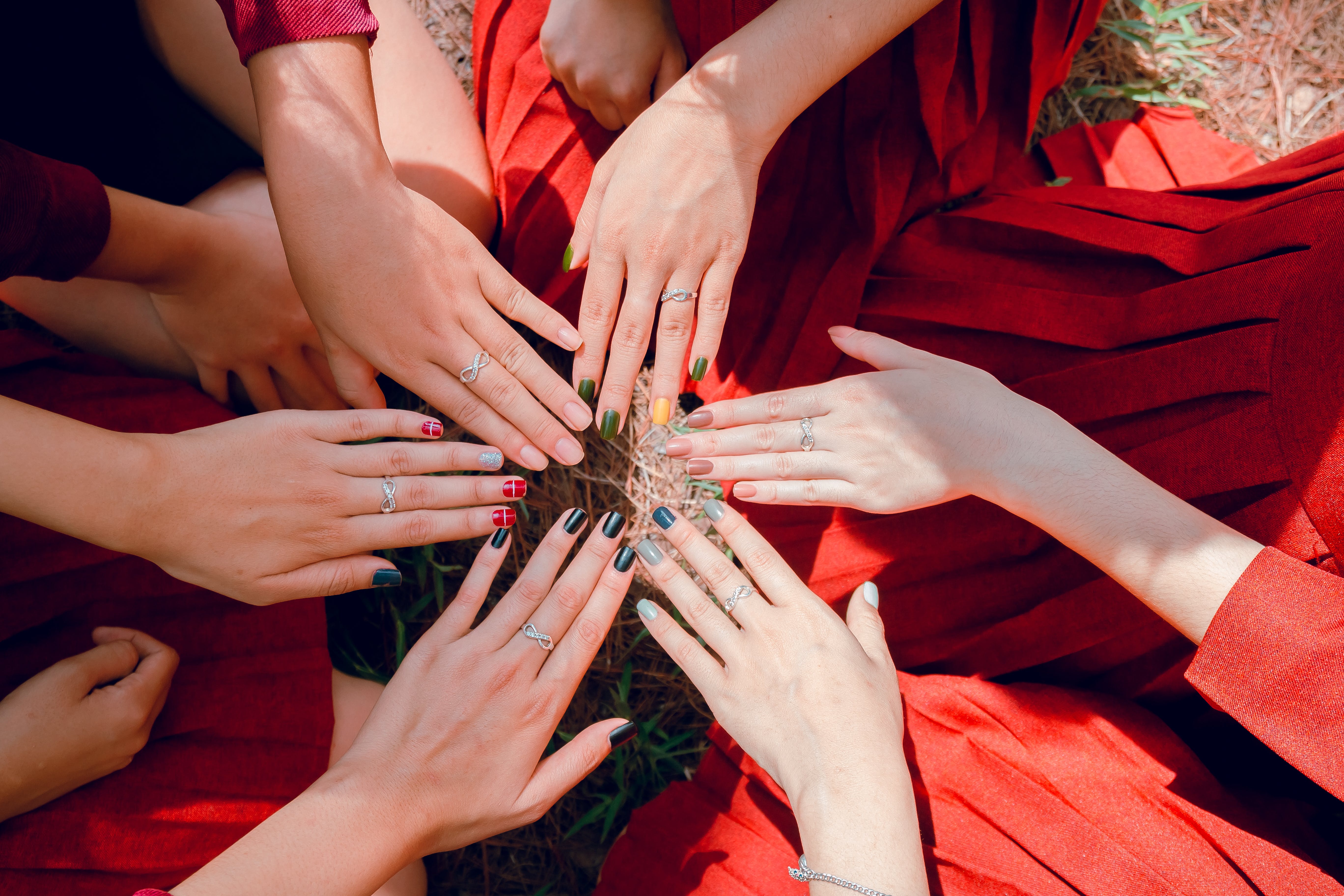 women in red dresses holding out their hands with stainless steel eternity rings