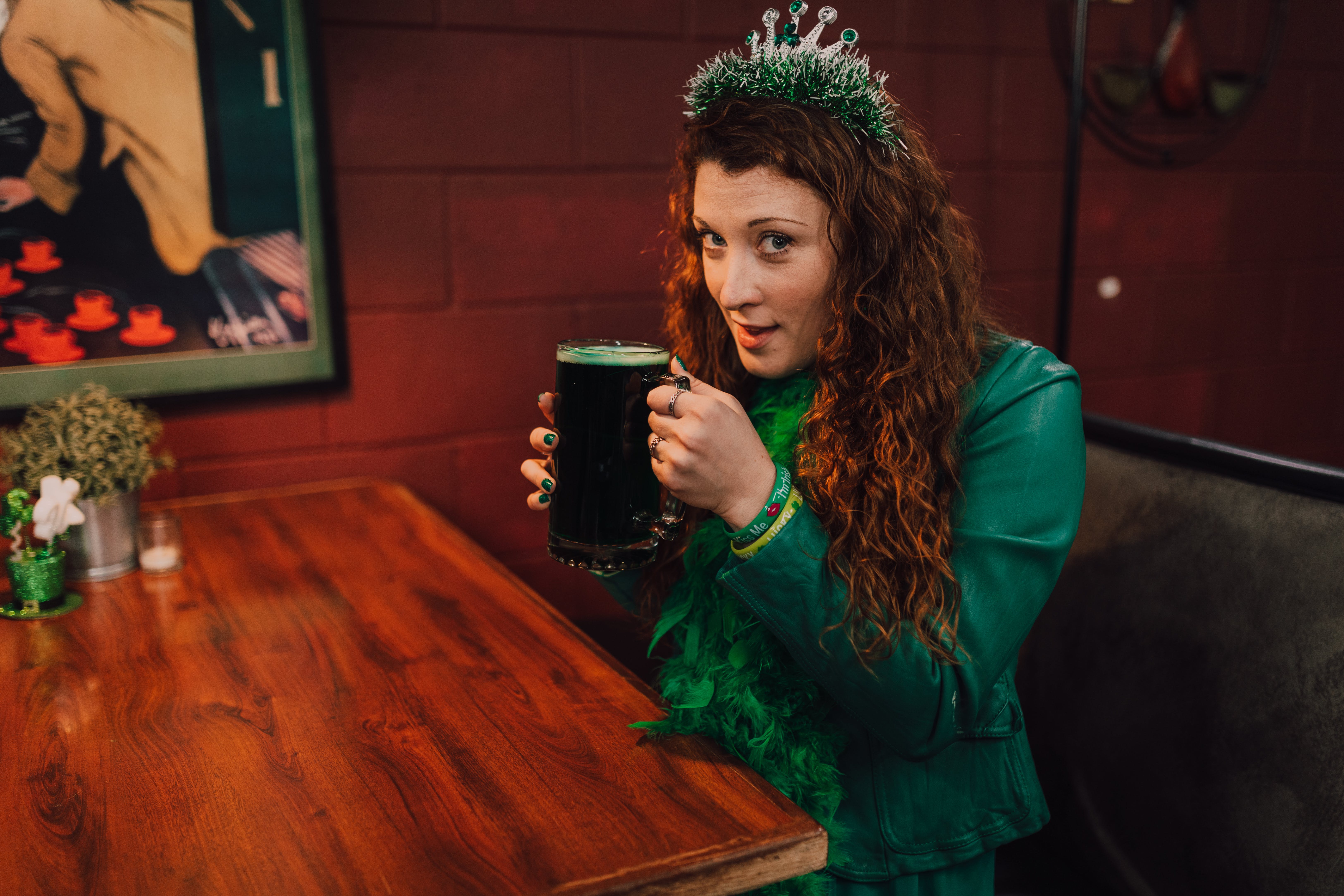 curly haired woman in a green St. Patrick's Day inspired outfit holding a beer mug