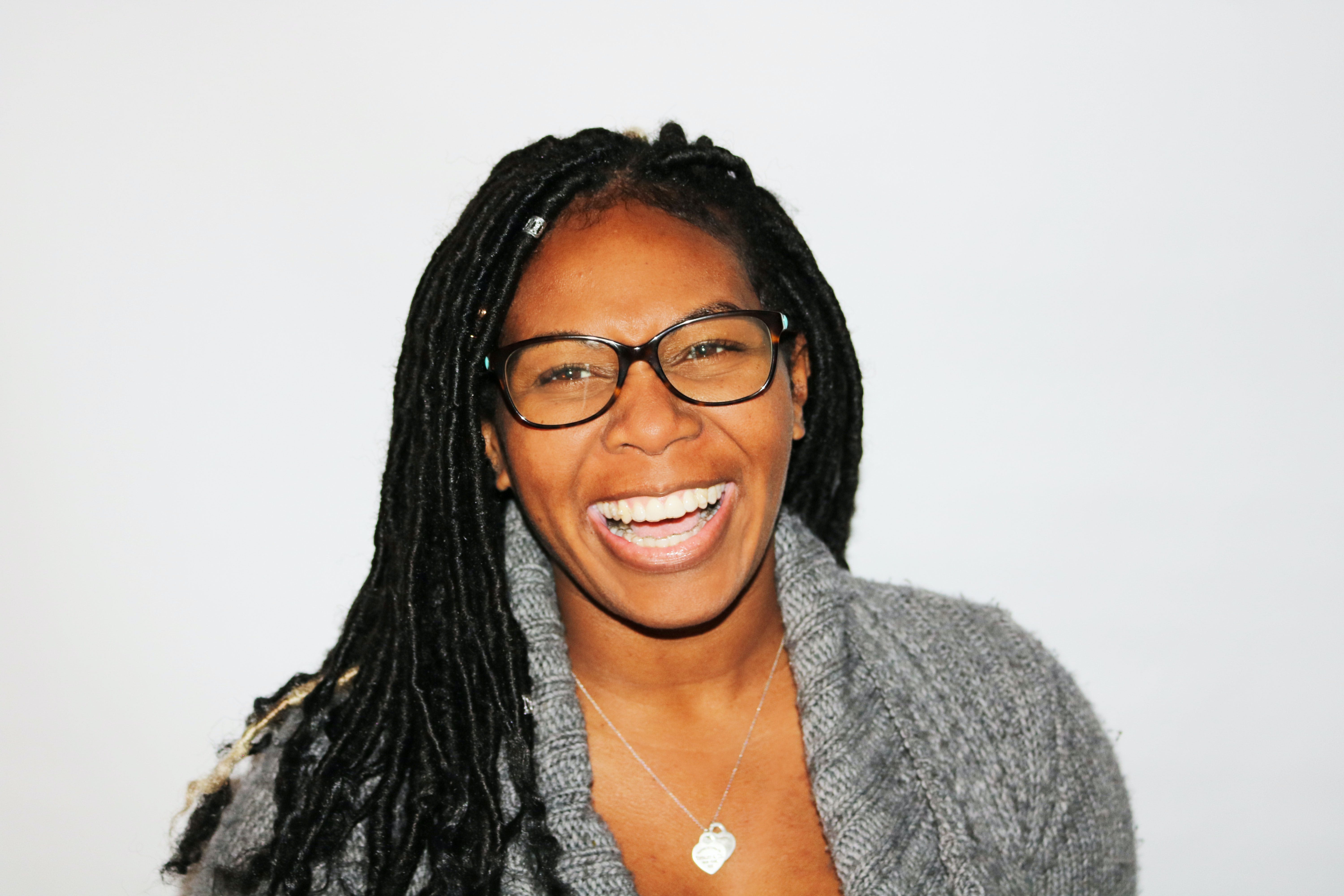 smiling woman wearing eyeglasses and a silver heart pendant necklace