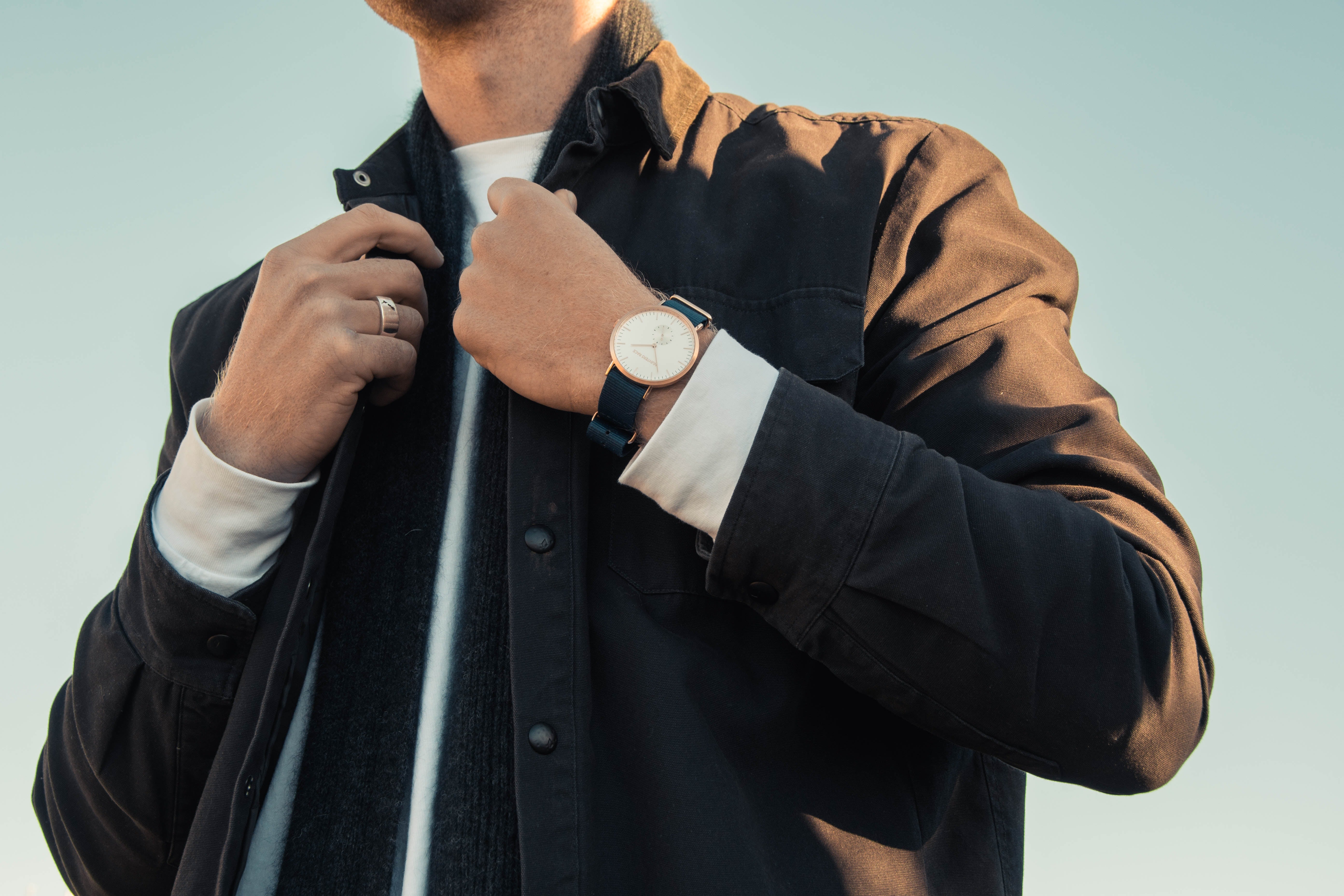 man wearing a black jacket, stainless steel ring and black watch