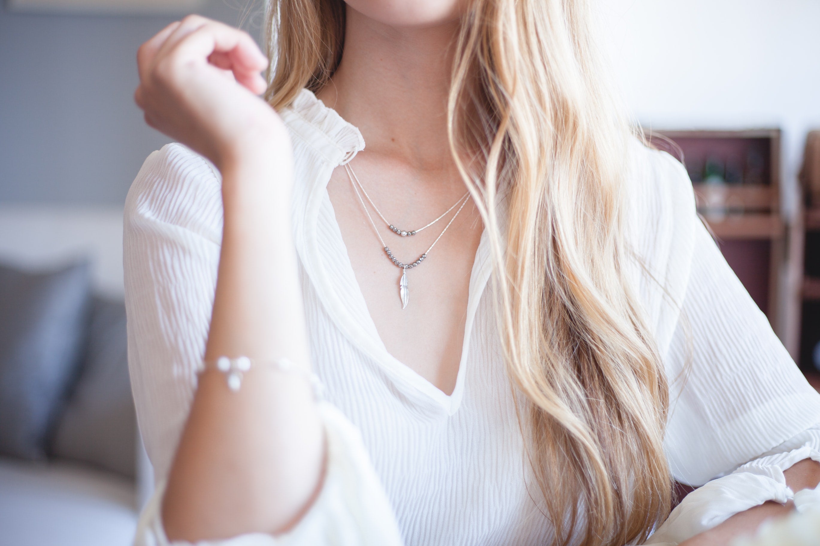 woman wearing white long-sleeved blouse and trendy necklaces