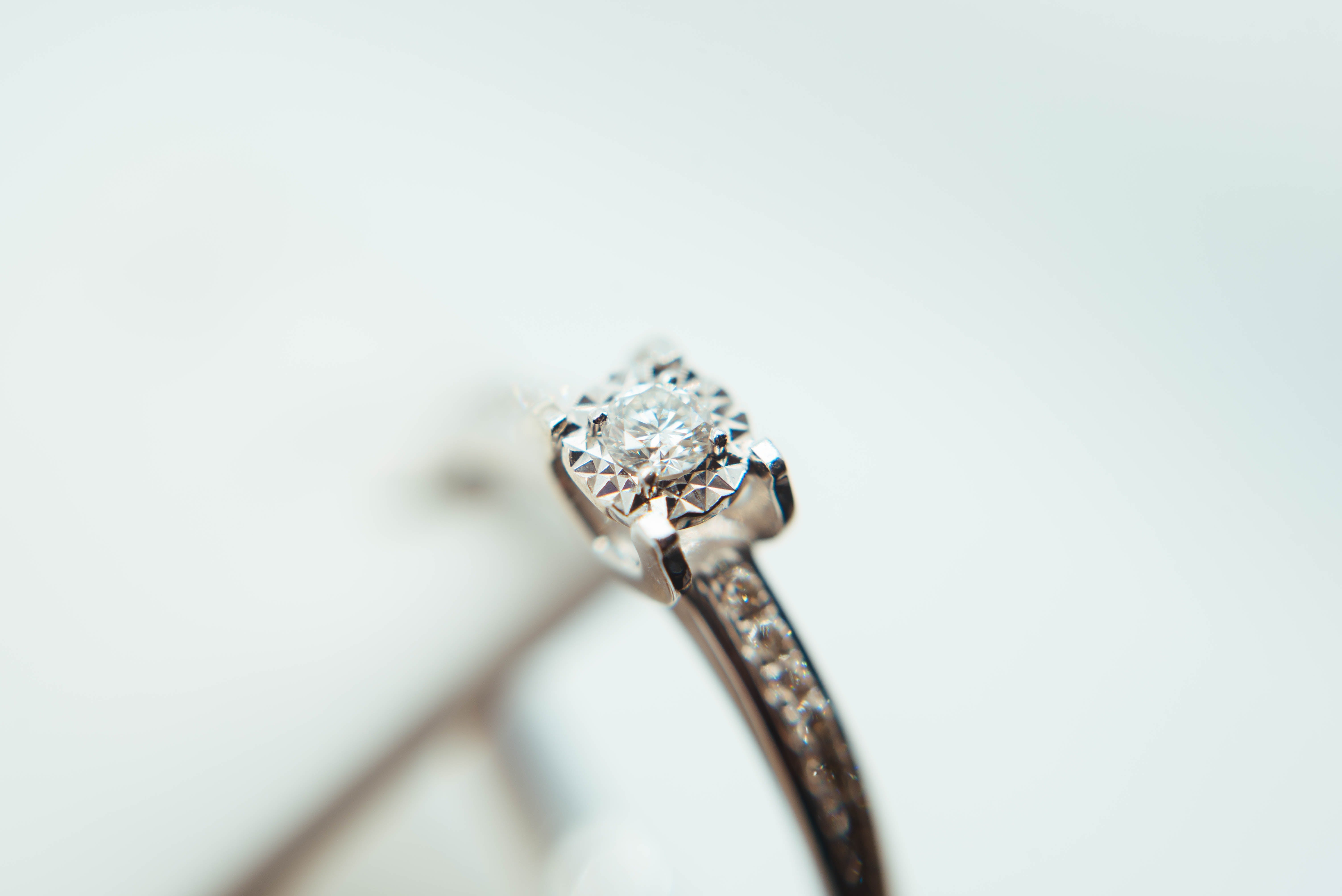 macro shot of a silver Moissanite engagement ring against white background