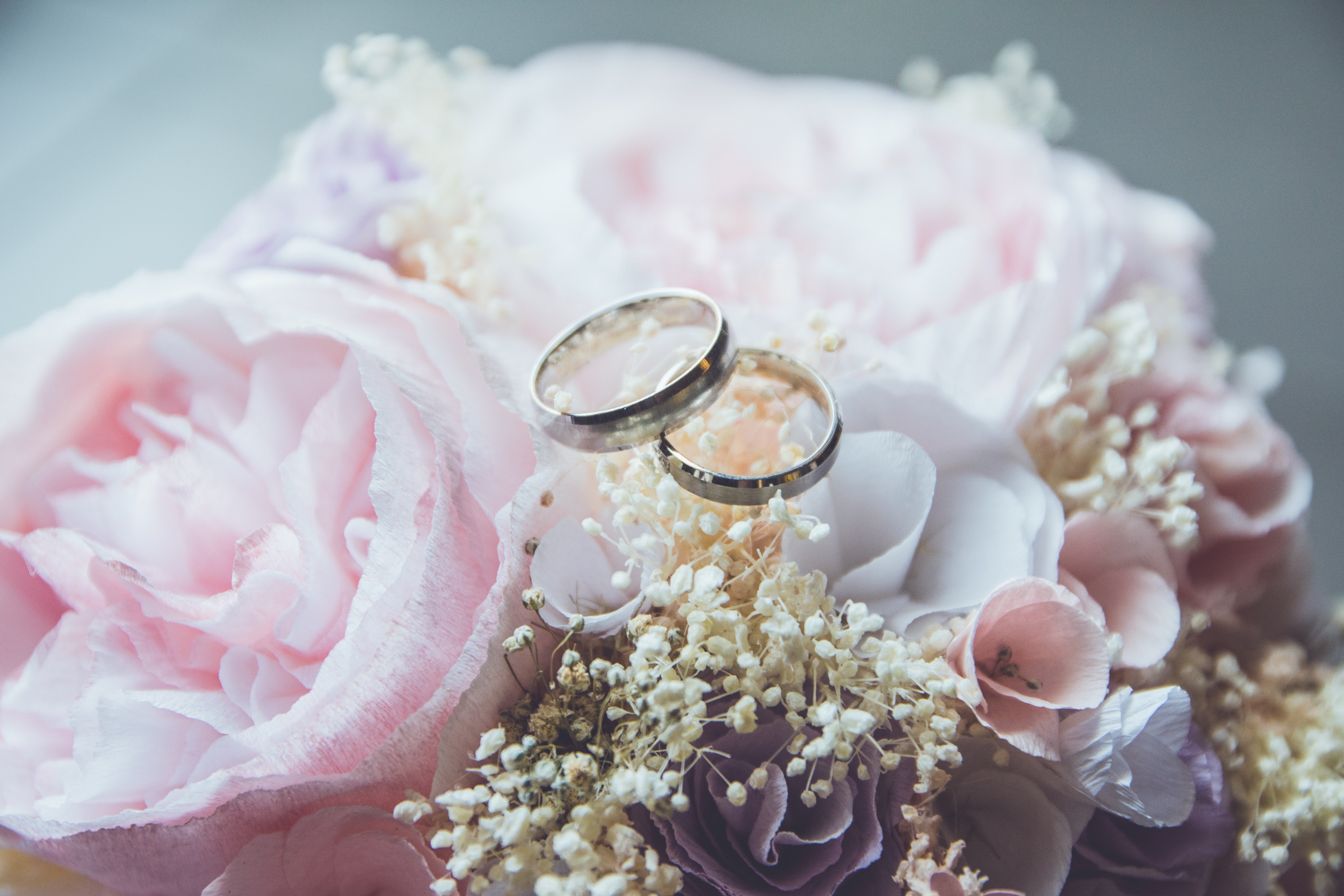 white gold wedding bands on top of a small bouquet of flowers