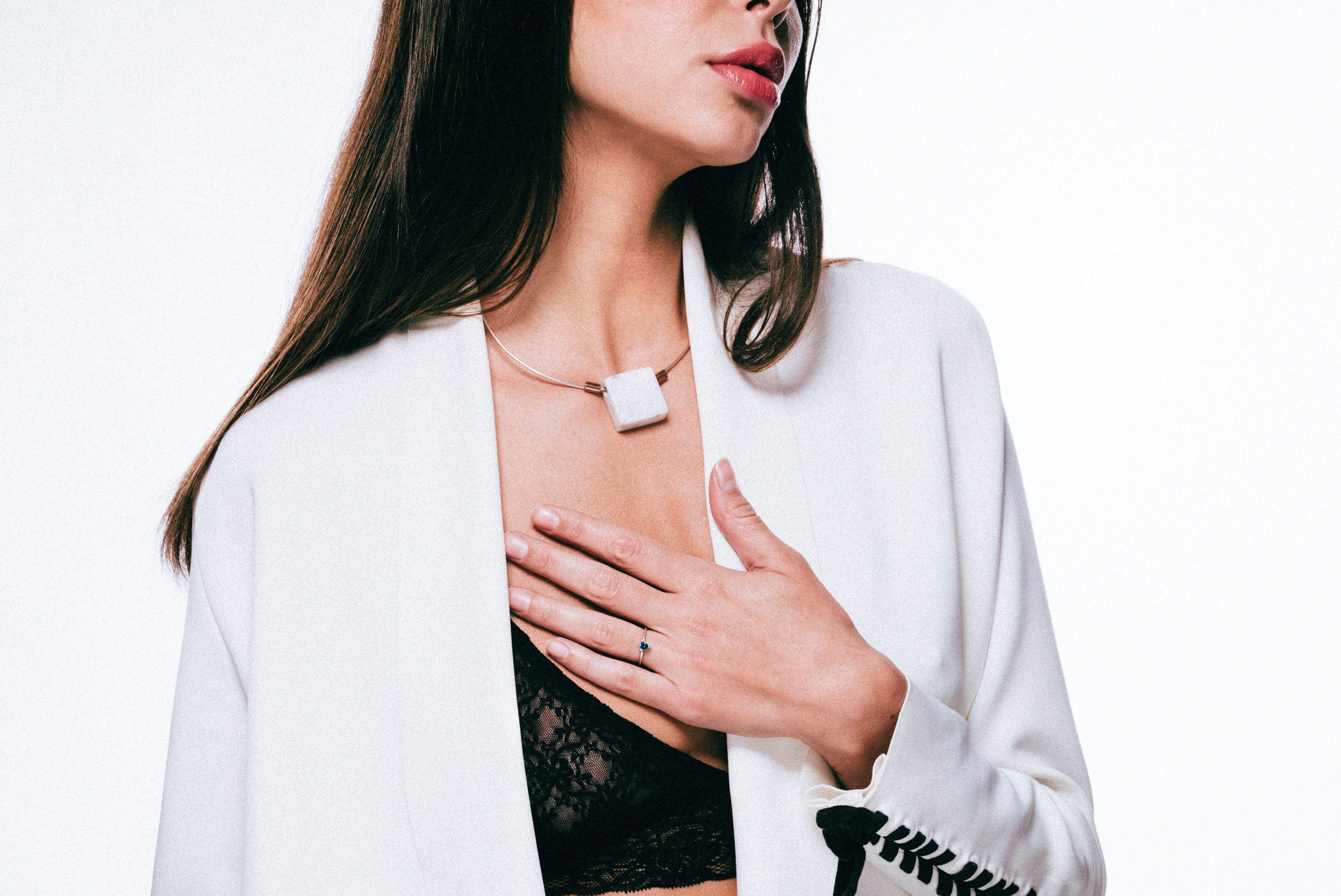 woman in a white blazer and black lingerie wearing a minimalist necklace and minimalist ring