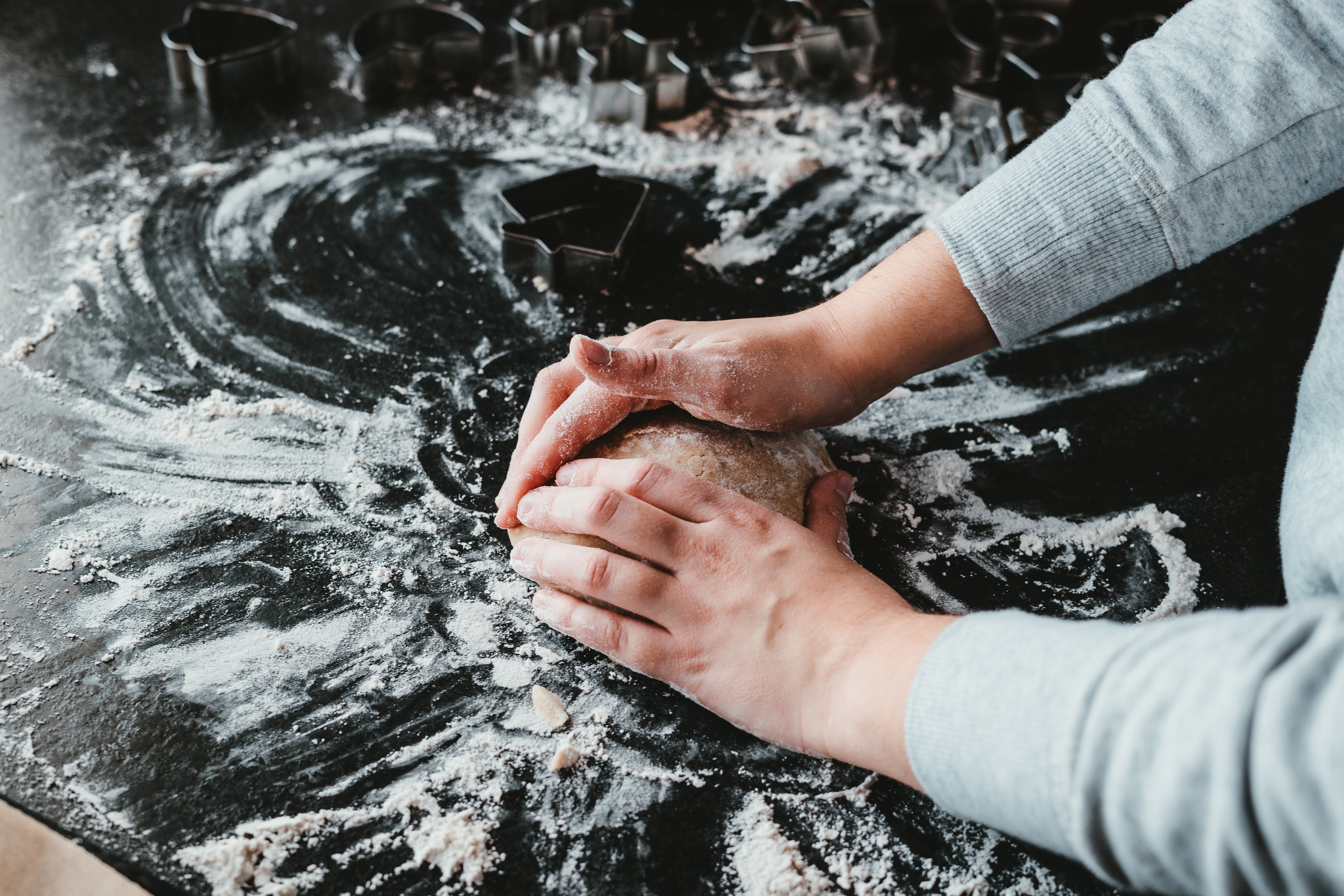 woman's hands kneading dough on a black surface